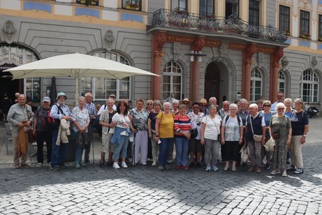 Reiseteilnehmer stehen vor dem Rathaus in Coburg, Vor dem Eingang stehen 4 rote S&auml;ulen, die einen Balkon mit schmiedeeisernem Ornamentegel&auml;nder tragenmitn S&auml;ulen