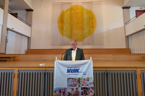 Älterer Mann in Anzug am Rednerpult mit VdK-Logo, im Hintergrund eine Bühne.