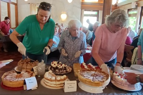 Das Vorstandsteam steht am Kuchenbuffet und verteilt die Kuchen an die Mitglieder