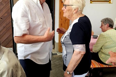 Ein gro&szlig;er Mann im wei&szlig;en Hemd und einem Strohhut gratuliert Marlies.