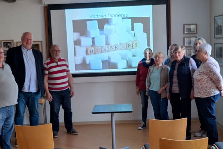 Teilnehmer stehen vor der Diabetes Leinwand