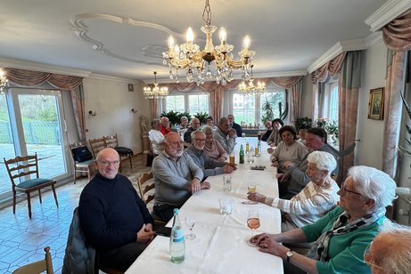 Viele gut gelaunte Menschen die um einen Tisch sitzen