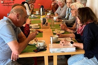 Die rechte Seite von 2 Tischtafeln mit Gästen bei Kaffee & Kuchen