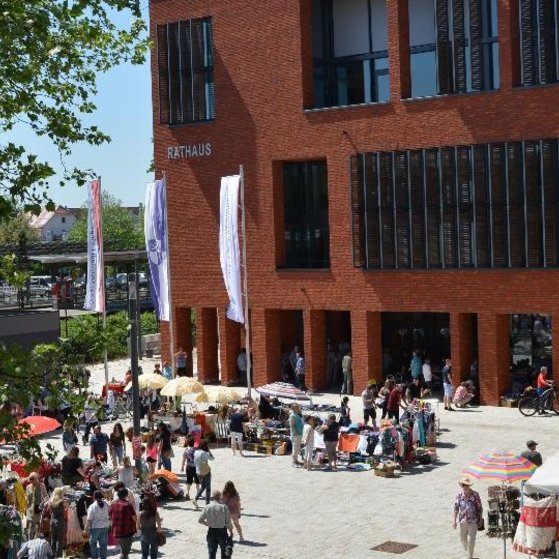 Das Bild zeigt das Rathaus von der &Uuml;berf&uuml;hrung her gesehen. Auf dem Vorplatz findet gerade ein Kleidermarkt statt.