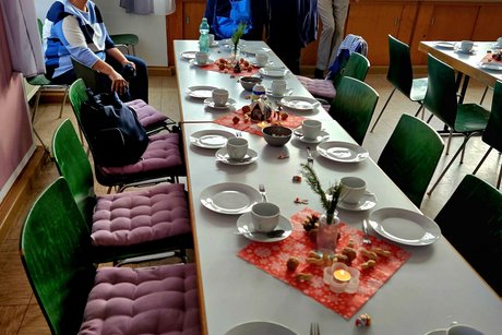 Geschmückter und weihnachtlich gedeckter Tisch, am Tischende sitzen ein paar Damen lässig im Gespräch.