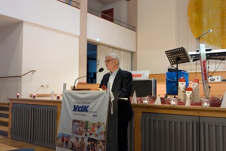 Älterer Herr steht an einem Rednerpult.