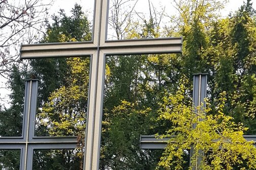 Volkstrauertag Drei mehrere Meter hohe Kreuze, von denen nur die oberen Teile sichtbar sind. Ein Kreuz wird teilweise von einem Baum verdeckt.