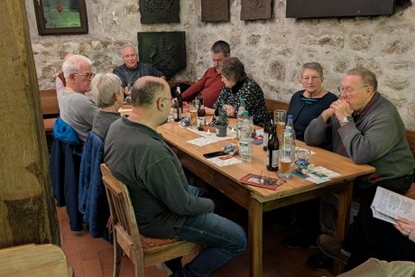 Auf diesem Bild sieht man Teilnehmer der Weihnachtsfeier an einem Tisch sitzen