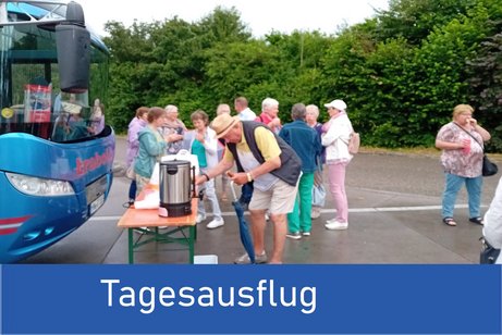 Bild zeigt viele Personen die sich am Tisch der vor einem Bus steht Kaffee holen