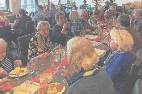 Gesellige Runde von VDK Mitgliedern an langen Tischen - es werden herzhafte Kleinigkeiten, Kaffee und Kuchen genossen. Im Hintergrund die musikalische Untermalung durch Musiker des Harmonika Spielrings.