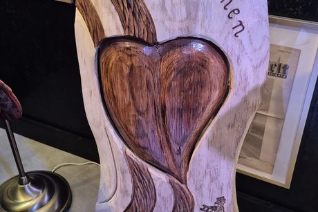 Holzschnitzerei in Herzform mit "Herzlich Willkommen"