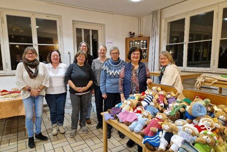 Das Foto zeigt unsere "Hoffnungsb&auml;ren" auf Tischen im Vordergrund. Im Hintergrund die fleissigen Strickerinnen und die Empf&auml;nger der B&auml;rchen