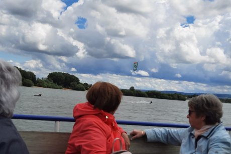 Zwei Frauen auf dem offenen Oberdeck beobachten Kitesurfer auf dem See.