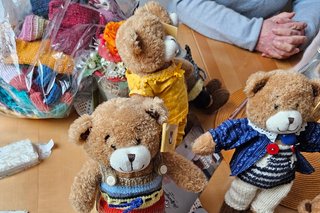 3 Teddy-Bären, die selbst gestrickte, bunte Kleidung tragen.