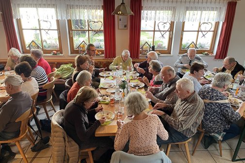 Personen sitzen am Tisch und essen