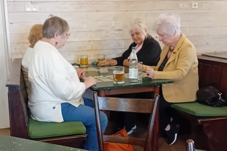 4 Frauen sitzen am Tisch und spielen Karten