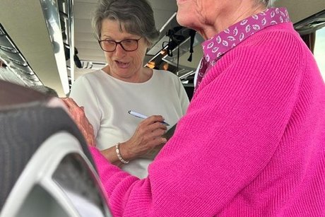 Zwei Ausschussmitglieder beim Einkassieren des Kostenbeitrags im Bus