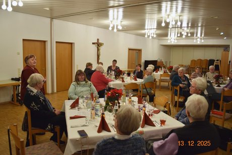 Panoramafoto des Festsaals mit mehreren Tischen, an denen &uuml;berwiegend &auml;ltere Damen sitzen; vorne h&auml;lt eine Frau eine Rede
