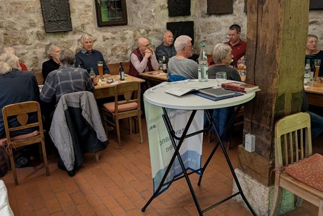 Hier sieht man Teilnehmer der Weihnachtsfeier miteinander an einem Tisch sitzen