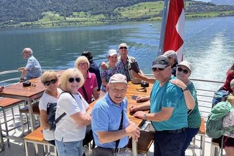 auf dem Schiff eine Teilnehmergruppe sitzt auf dem Schiff mit Blick auf See und Bergpanorama