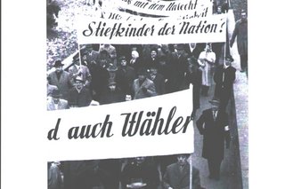 Bild zeigt einen Protestzug mit beschrifteten Schildern von den 1950 Jahren