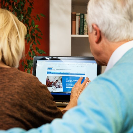 Ein älteres Paar am Computer, auf dem Bildschirm sieht man die Facebook-Seite des VdK Deutschland