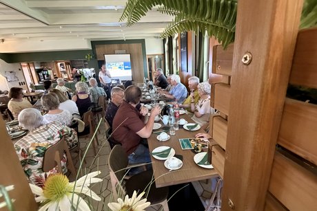 Besucherinnen und Besucher des Sommerfests sitzen an Tischen im Restaurant Hasenheim