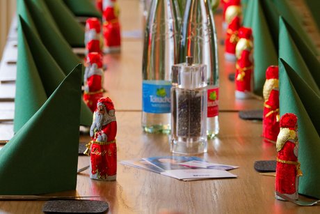 Tischdeko bei der Weihnachtsfeier: gr&uuml;ne Servietten und rote Schoko-Nikol&auml;use