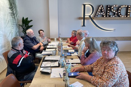 Personen sitzen am Tisch und unterhalten sich