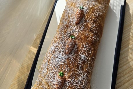 Eine Aufnahme von einer Bisquittrolle mit kleinen Marzipan Rübchen darauf.