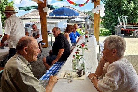 An Tischen mit wei&szlig;en Tischt&uuml;chern sitzen die G&auml;ste, es gibt Kaffee und kuchen.