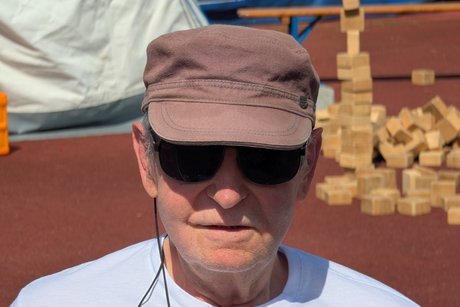 sitzt im Rollstuhl mit Sonnenbrille und M&uuml;tze
