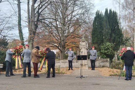 Soldaten in Ausgehuniform richten den Kranz aus.