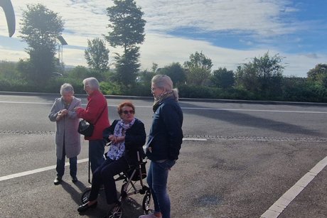 4 Mitreisende stehen bzw. sitzen vor dem Bus und unterhalten sich