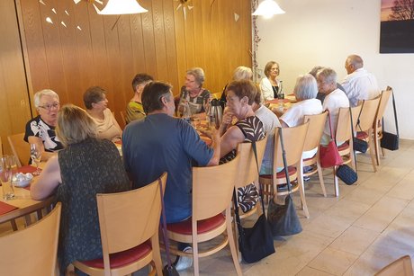 Mehrere Personen sitzen um eine gedeckte Kaffeetafel