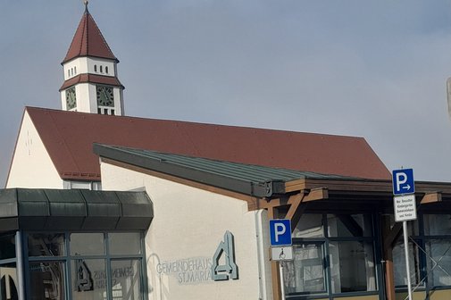 Das Gemeindehaus St. Maria in Meckenbeuren mit dem Kirchturm im Hintergrund.