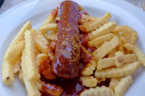 Das Bild zeigt eine Currywurst mit Pommes