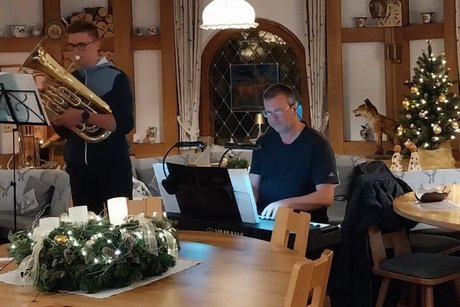 Ein Euphonium als Soloinstrument Moritz Zimmermann stehend am Euphonium und Arne Marterer sitzend am Keyboard, davor ein großer Adventskranz auf einem runden Tisch mit einer brennenden weißen Kerze