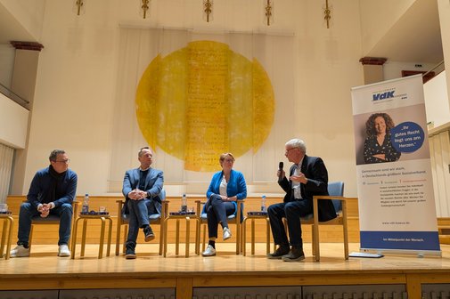 Auf einem Podium sitzen drei Politiker &ndash; zwei M&auml;nner und eine Frau &ndash; und diskutieren lebhaft mit dem Moderator.
