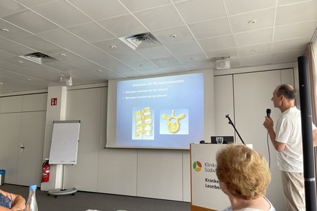 Der Arzt erkl&auml;rt anhand von Folien die Entstehung von R&uuml;ckenschmerzen