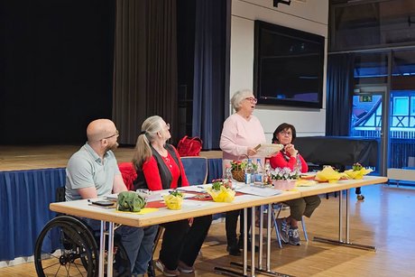 Hauptversammlung VdK OV Echterdingen 2026 Tischreihe des vierköpfigen Vorstands, während eine ältere Dame des Vorstands aufsteht und eine Rede hält