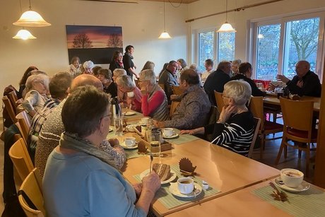 Mehrere Personen sitzen um gedeckte Kaffeetafeln