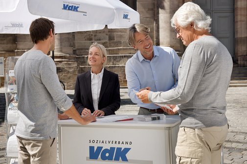 Eine Mitarbeiterin und ein Mitarbeiter an einem VdK-Infostand informieren gerade zwei interessierte Passanten. 