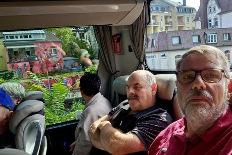 Im Bus sitzen zwei M&auml;nner und eine Frau in der letzten Reihe.