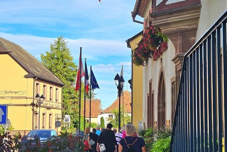 Eguisheim ein Ort inm Elsass bei sch&ouml;nsten Wetter in der Fussg&auml;ngerzone laufen die Mitglieder an den H&auml;userfasaden entlang, Fahnen wehen im Wind