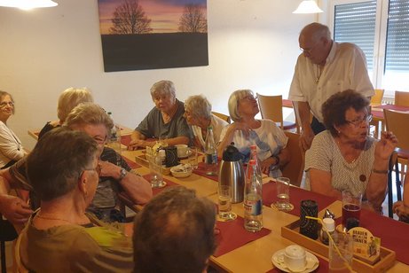 Mehrere Personen sitzen um eine gedeckte Kaffeetafel