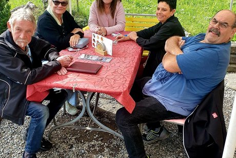 unter einem Sonnenschirm sitzen 5 Mitglieder und sind fr&ouml;hlich.