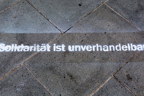 Weißer Laserschriftzug auf dem Boden "Solidarität ist unverhandelbar"