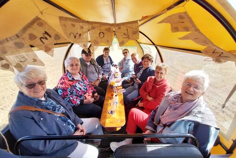 Gruppenbild vom Kutschbock aus auf die in der Kutsche sitzenden älteren Personen, die in die Kamera lächeln.