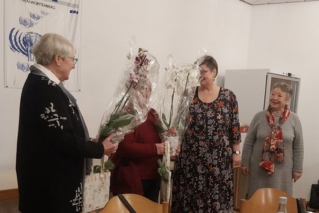 Vier Frauen stehen nebeneinander, zwei von ihnen halten eingepackte Orchideenpflanzen in den H&auml;nden.
